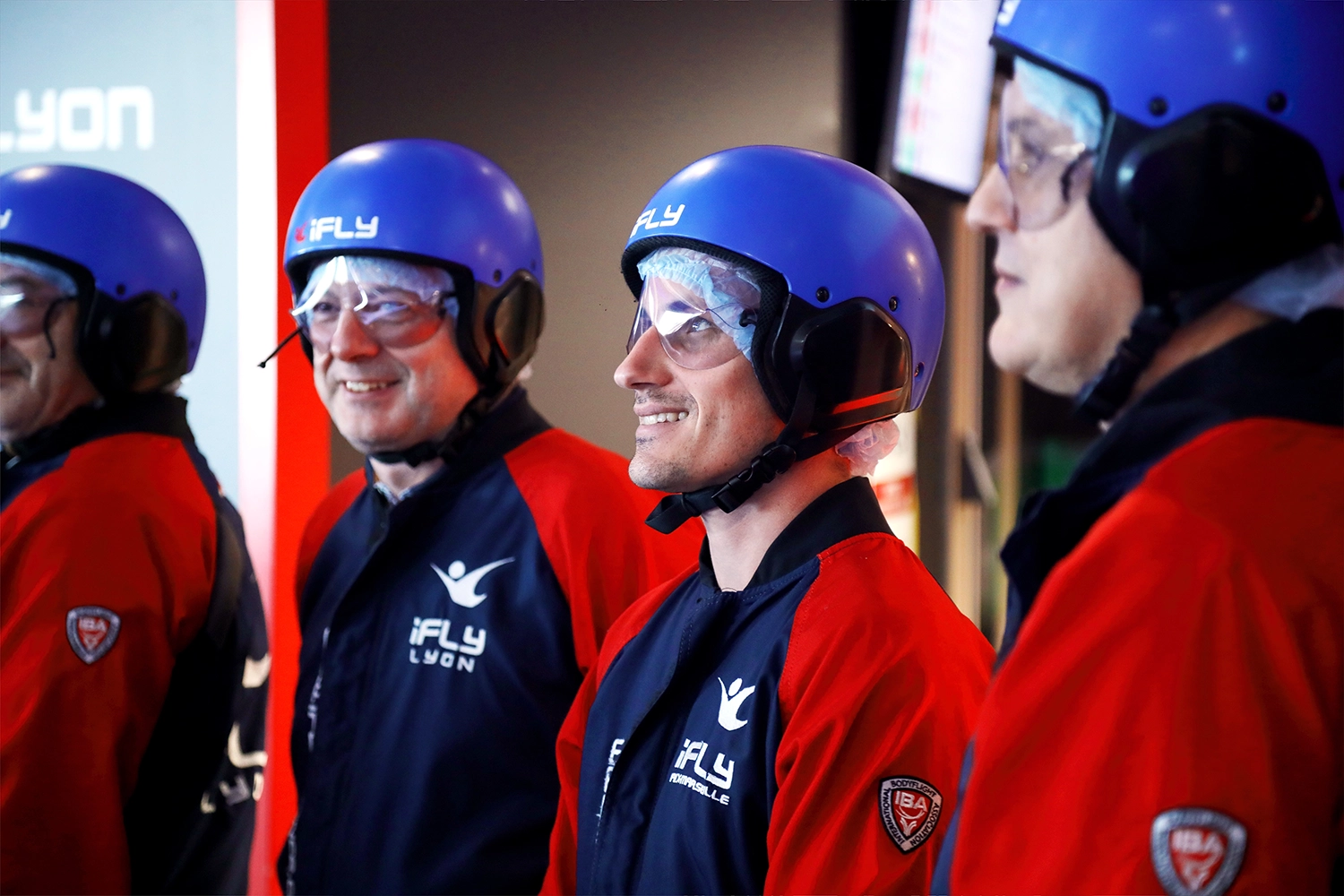 Participants souriants portant des casques de vol chez iFLY Lyon, prêts pour leur expérience de vol.