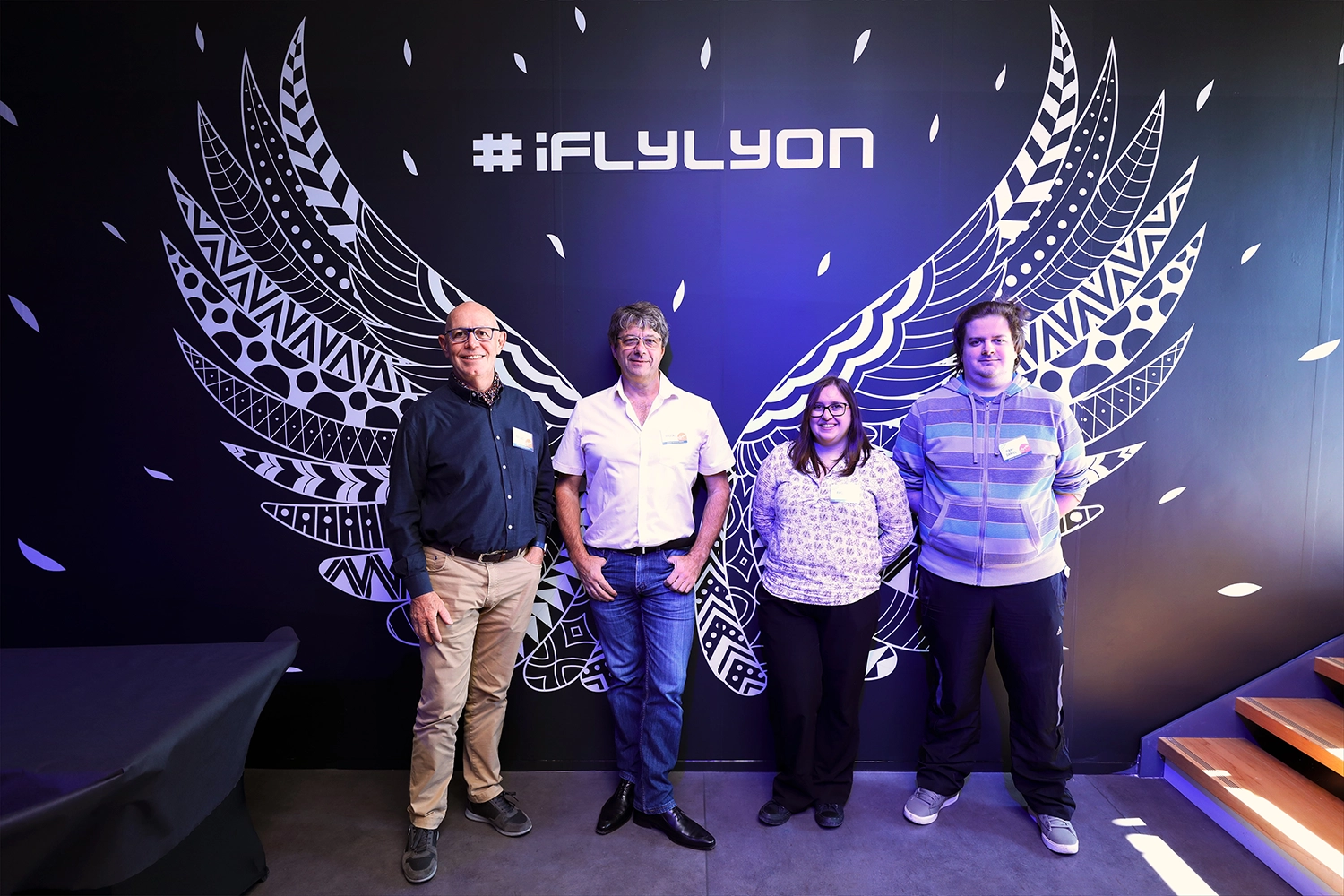 Participants posant devant le mur décoratif d'iFLY Lyon lors d'un événement d'entreprise.