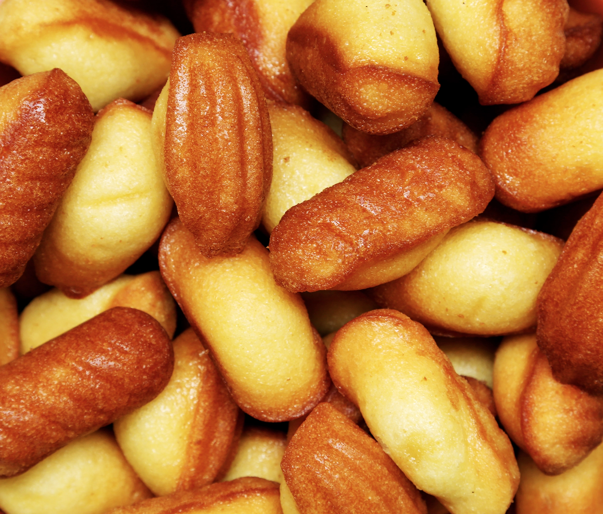 Gros plan de madeleines de St Michel dans des tons dorés et cuivrés, photographiées en studio pour une mise en avant de produits.