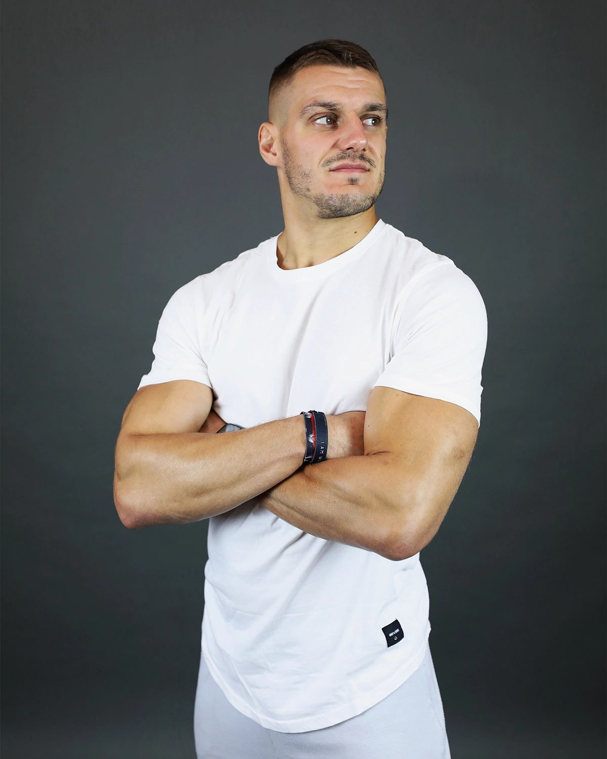 Portrait studio d'un coach sportif en T-shirt blanc, bras croisés.