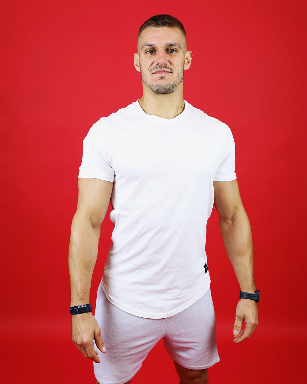 Portrait d'un coach sportif en tenue blanche sur fond rouge pour un book professionnel.