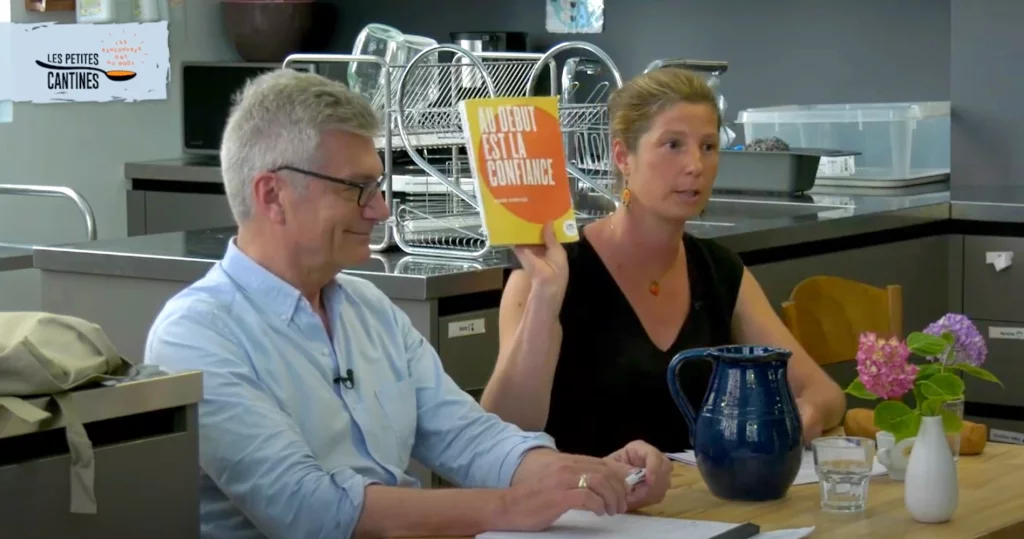 Diane Dupré La Tour et Mark Hunyadi lors d'une conférence, avec Mark présentant un livre intitulé 'Au début est la confiance'.