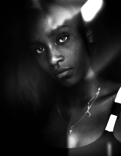Gros plan en noir et blanc d’une femme dans une lumière contrastée.
