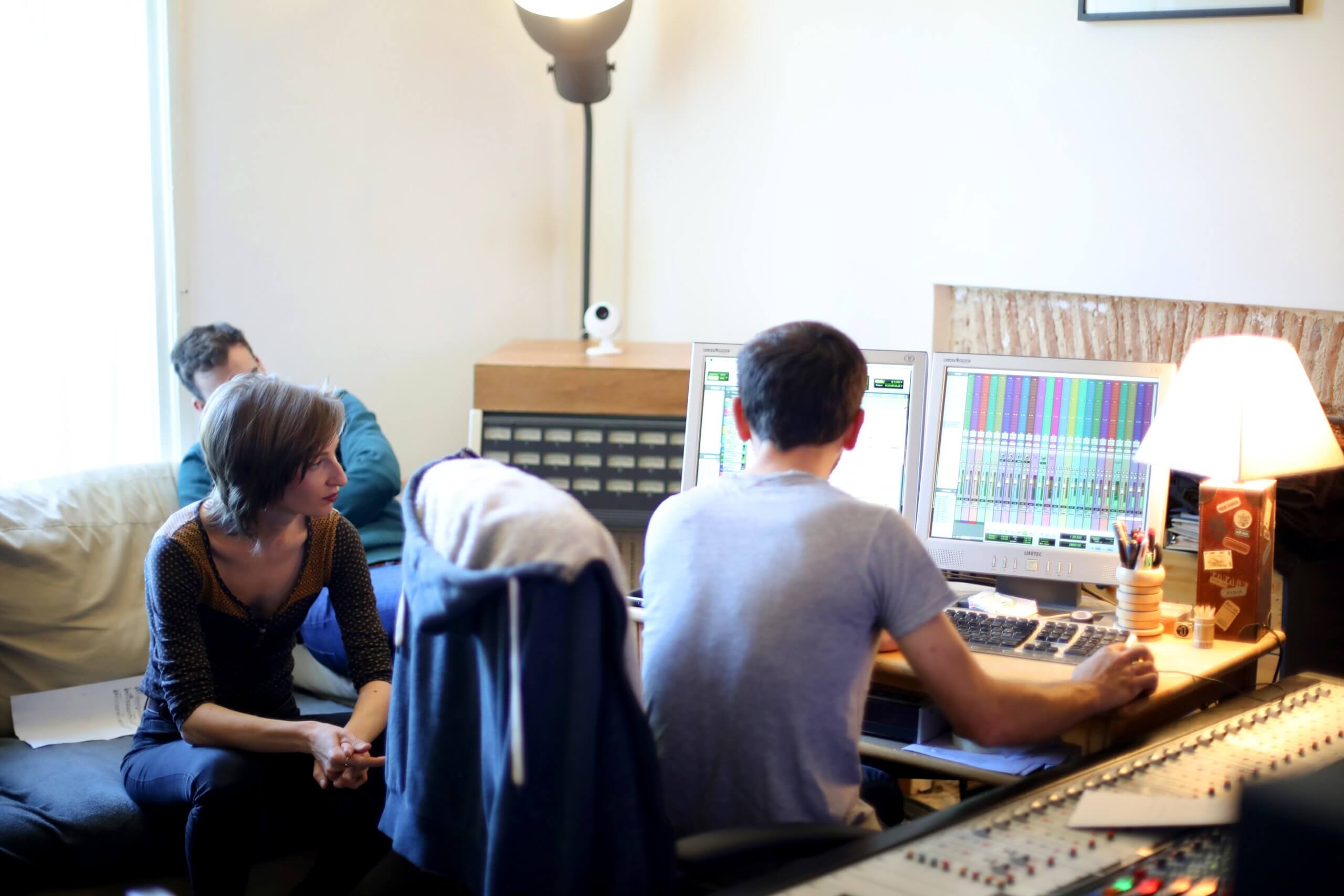 Session EP de Perrine Missemer - travail autour de la console Plusieurs personnes réunies autour d’une console et d’écrans affichant les pistes audio pendant une session d’enregistrement.