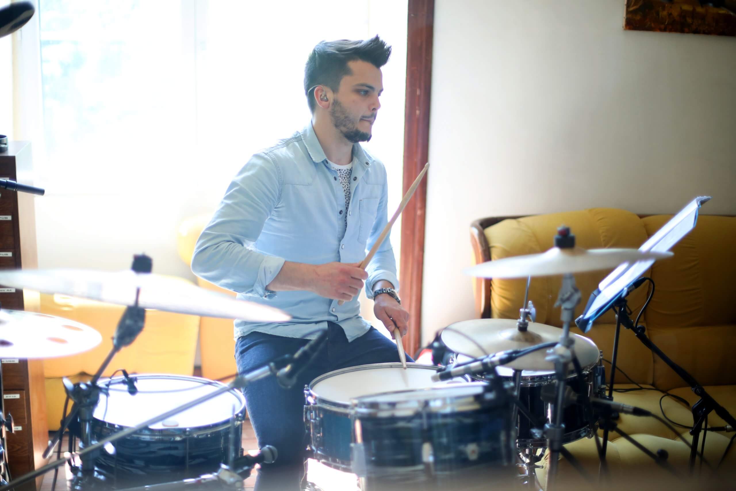 Session EP de Perrine Missemer - batteur en studio Un batteur joue avec un casque devant sa batterie, entouré de microphones et d’un pupitre.