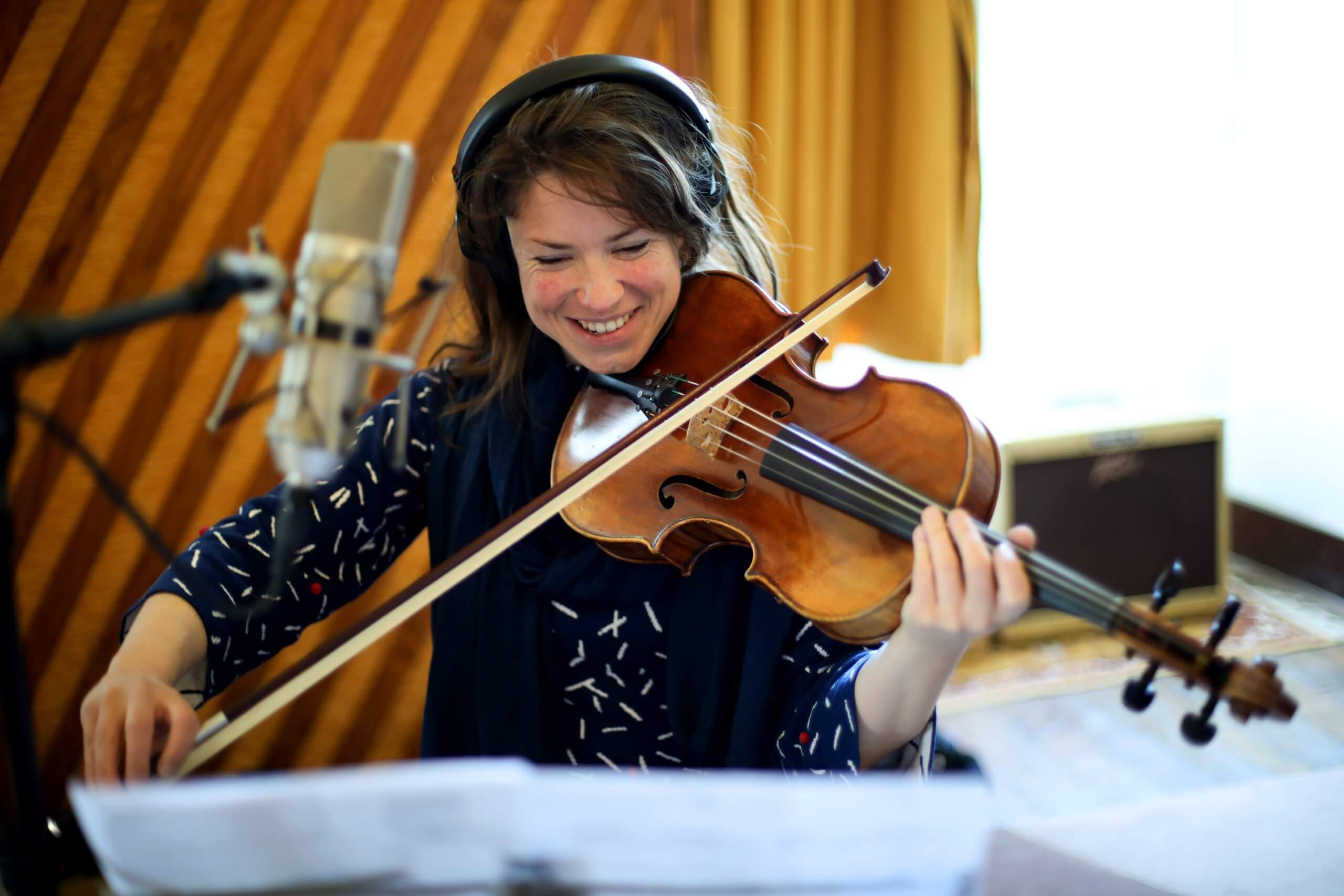 Session EP de Perrine Missemer - violoniste en studio Une violoniste souriante joue devant un microphone, avec un casque, pendant la session d’enregistrement de l’EP de Perrine Missemer.