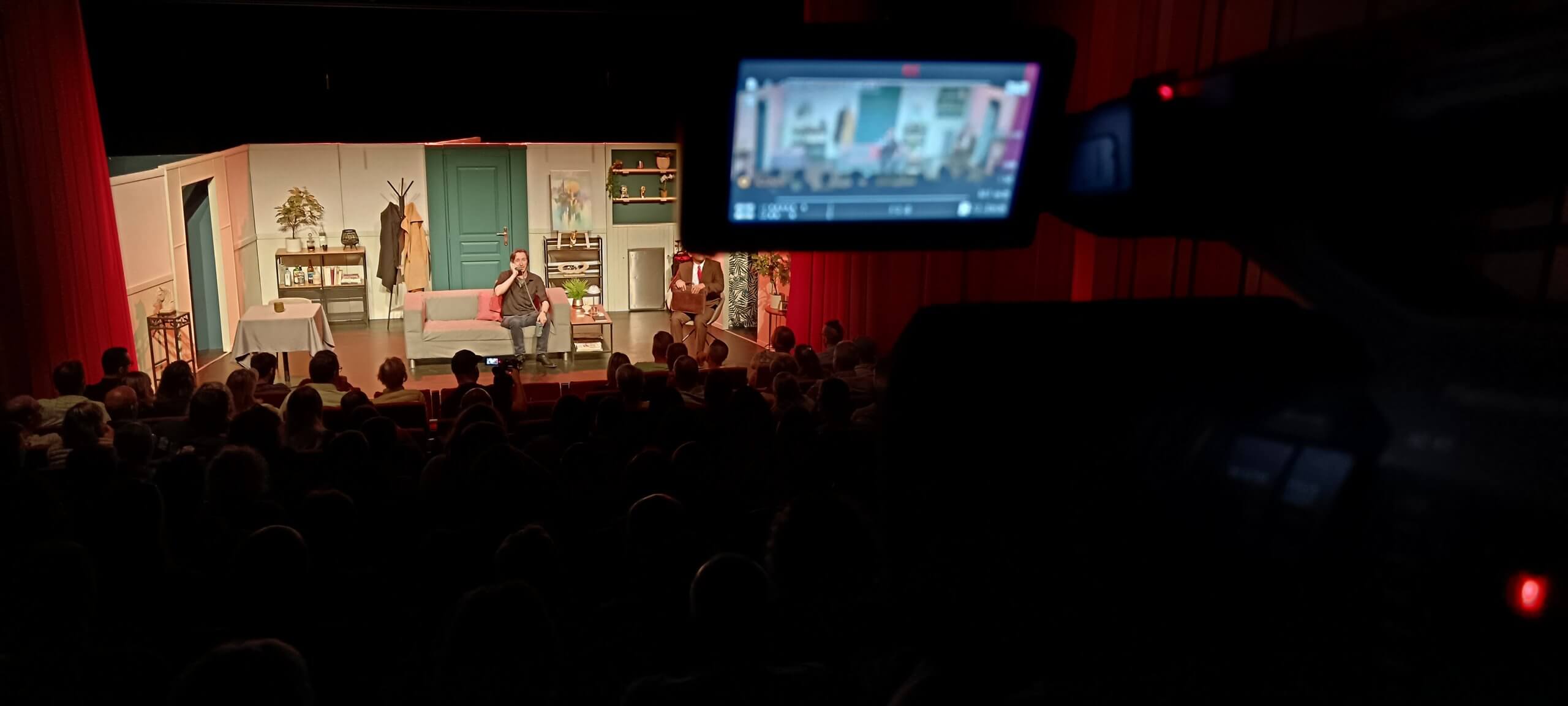 Captation du Dîner de cons au Théâtre à l’Ouest à Décines Caméra filmant une scène du Dîner de cons au Théâtre à l’Ouest à Décines, avec le public au premier plan.