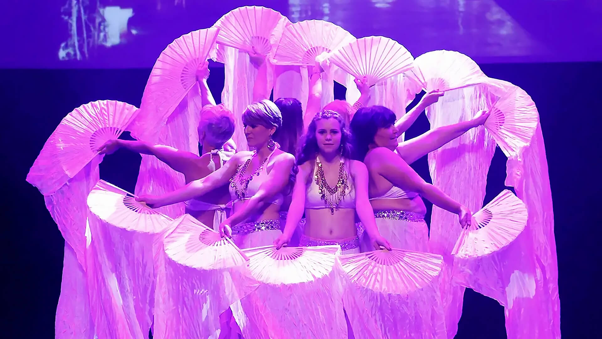 Captation vidéo d'un spectacle de danse orientale à Lyon par Les FasCinés Production Groupe de danseuses réalisant une performance de danse orientale avec des éventails sur scène, capturé lors d'une captation vidéo par Les FasCinés Production à Lyon.