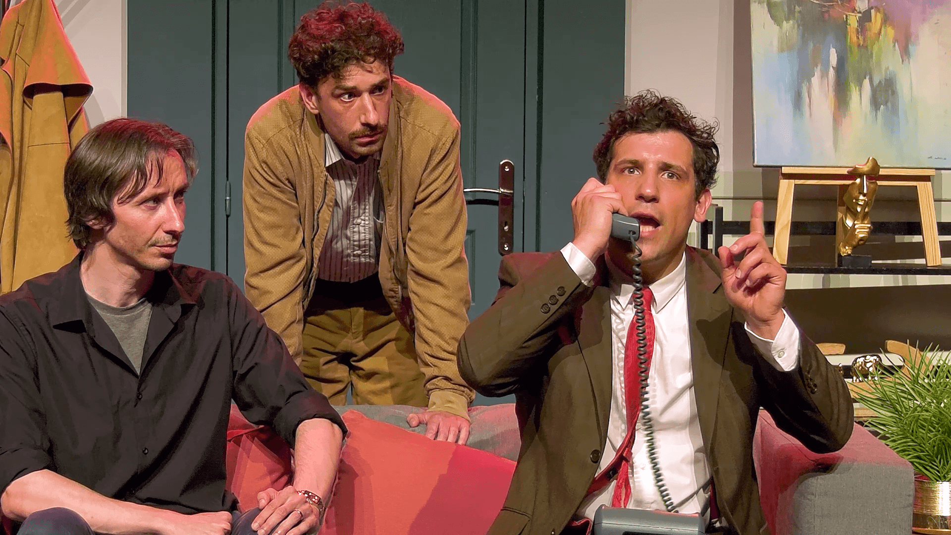Captation de théâtre : plan rapproché sur le jeu des comédiens Trois comédiens dans un décor de salon, dont un parlant au téléphone, dans un plan rapproché issu d’une captation de théâtre.